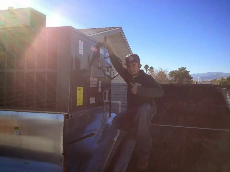 HVAC technician performing AC Tune-Up on a rooftop unit in Olivarez